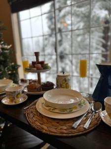 une table avec des assiettes et de la vaisselle sur celle-ci et un sapin de Noël dans l'établissement YoBee! Park Reservation Included! Heart of Yosemite - Homey Studios and Breakfast, à Yosemite West