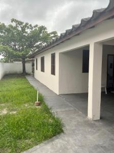 a white building with a tree in the yard at Casa em Shangri-lá perto da praia para até 10 pessoas in Pontal do Paraná