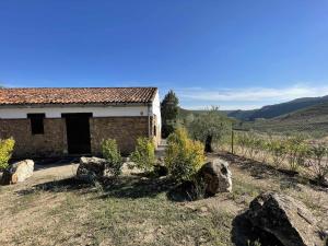 una pequeña casa con rocas delante de ella en La Alberguería complejo rural, en Cañamero