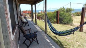 a porch with two chairs and a hammock on a house at Agua Corazones in San Luis
