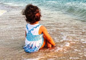 uma menina sentada na água na praia em Chalet with sea view استوديو باطلالة على البحر em Makman