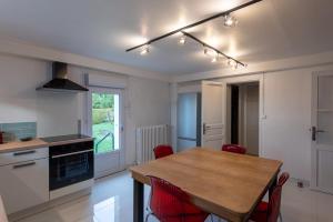 a kitchen with a wooden table and red chairs at Au 9ème Art in La Rochefoucauld