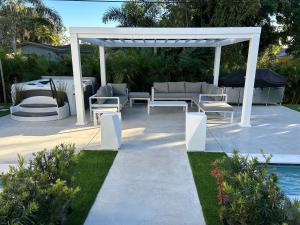a pergola with a table and chairs next to a pool at Men only clothing option guesthouse near Wilton Manors in Fort Lauderdale
