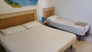 een kamer met 2 bedden en een blauwe vaas op een tafel bij Residence Villa delle Rose in Lampedusa