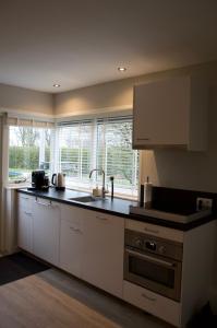 a kitchen with white cabinets and a counter top at Vakantiehuis 't Hertenkamp in Ouddorp