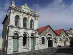 een groot wit gebouw met groene deuren aan een straat bij Rosies Place in Oamaru +8 foto's