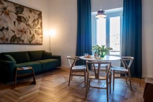 sala de estar con sofá verde, mesa y sillas en Dimora San Bartolomeo - Design, Panoramic View & Culture en Roma