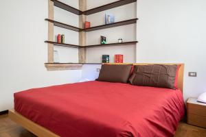 a bedroom with a red bed with shelves on the wall at Casa Turandot Verona in Verona