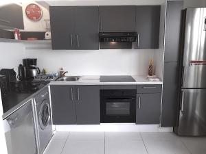 cocina con armarios negros, fregadero y lavavajillas en le BLUE LAGOON, en Saint Martin