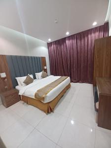 a bedroom with a large bed and purple curtains at سرايا ان شاليهات وغرف فندقية in Jazan