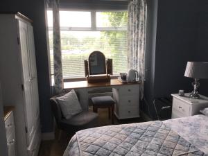 a bedroom with a bed and a desk and a window at TJ’s Cottage in Enniskillen