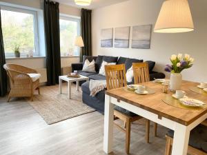 ein Wohnzimmer mit einem blauen Sofa und einem Tisch in der Unterkunft Strandhaus Nordseebrandung Fewo A2.2 in Cuxhaven
