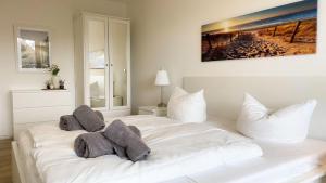 ein weißes Bett mit Kissen darauf im Schlafzimmer in der Unterkunft Strandhaus Nordseebrandung Fewo A2.2 in Cuxhaven