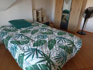 um quarto com uma cama com um edredão verde e branco em Belle Vue em Le Mans