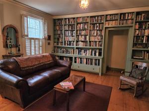 sala de estar con sofá de cuero y estanterías llenas de libros en The Inn on Primrose Hill, en Belfast