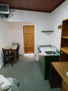eine Küche mit einem Waschbecken, einem Tisch und einer Tür in der Unterkunft Hotel Atlantic in Mar de Ajó