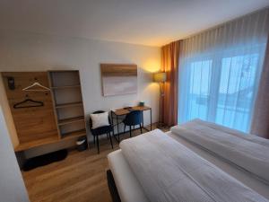 Habitación de hotel con cama, escritorio y ventana en Pension fein & sein, en Schwarzsee