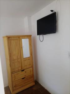 a television on a wall next to a wooden cabinet at Hotel Atlantic in Mar de Ajó