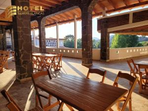 a wooden table and chairs in a room with windows at Hotel Tierras Blancas in Valle de Bravo
