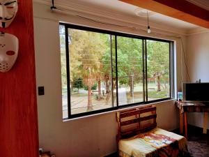 a room with a large window with a bed and a desk at La Casita Feliz...!!! in Cochabamba
