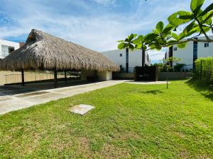a hut with a grass roof on a lawn at Casa en condominio Bahia Solero - Torrosa in Ricaurte