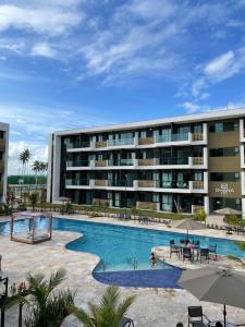 ein Schwimmbad vor einem Gebäude in der Unterkunft Flat ESTUDIO de LUXO - Praia de Muro Alto - Piscinas - Ideal para CASAIS, famílias com crianças - ap COMPLETO - AR COND, WI FI, NETFLIX, ESTACIONAMENTO - 400 mt do MAR in Porto De Galinhas