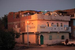 Carmah Guest house في أسوان: مبنى به الكثير من النوافذ وباب أخضر