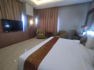 Habitación de hotel con cama y TV de pantalla plana. en Rylich Panorama Hotel, en Sorong