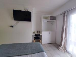 1 dormitorio con 1 cama y TV en la pared en Muriel en San Miguel de Tucumán