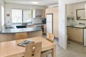 a kitchen with a wooden table and a counter top at Kings Way Apartments in Caloundra