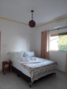 1 dormitorio con 1 cama blanca grande y ventana en Pousada Albuquerque, en Jijoca de Jericoacoara