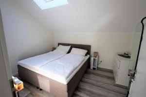 1 dormitorio con 1 cama con sábanas blancas y ventana en Meeresblick-Strandkieker-Haus-3-WE-45 en Hohwacht