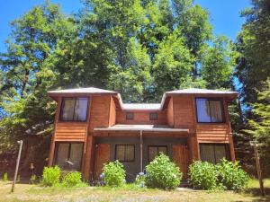a wooden house with trees in the background at Townhouse Millatray in Caburgua