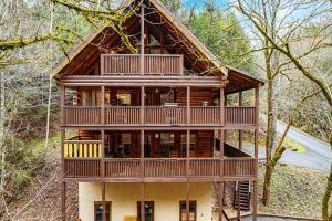 a large wooden house in the middle of the forest at Voted #1 Cabin in Smokys! Spa, Arcade, Private, Creek, King Beds in Sevierville