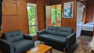 a living room with two chairs and a couch and a bed at Gumnut Glen Cabins in Yeppoon
