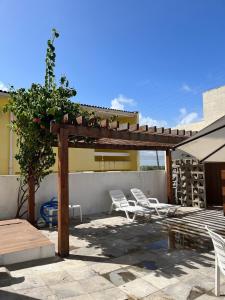 a patio with white chairs and a wooden pergola at Flatsportojjp - Flat Cupe Beach in Porto De Galinhas