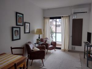 een woonkamer met stoelen en een tafel en een raam bij Departamento boutique en Salta in Salta