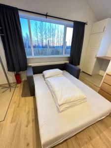 a bed in a room with a large window at Garður - Birta Rentals in Hella