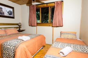 two beds in a room with a window at Hippo Waterfront Lodge in Nelspruit