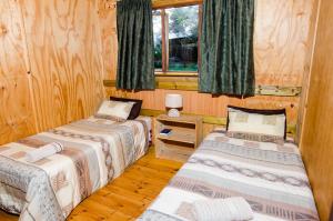 Hippo Water Front Lodge في نيلسبروت: ثلاثة أسرة في غرفة بجدران خشبية