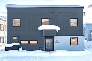 Una casa negra con nieve en la parte delantera. en JL HOUSE Kutchan en Kutchan