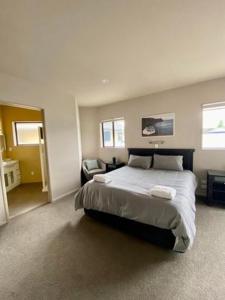 a bedroom with a large bed and a chair at Battys Road Lodge in Blenheim