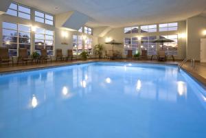 a large swimming pool in a hotel with tables and chairs at GrandStay Hotel & Suites - Glenwood in Glenwood