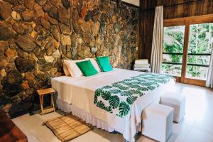 1 dormitorio con cama y pared de piedra en Glamping Mangarito en Iporanga
