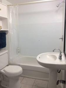 a white bathroom with a toilet and a sink at La cachette de la rivière au saumon et spa in Scotstown +27 photos