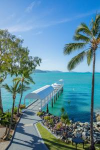 a pier next to the ocean with palm trees at Coral Sea Marina Resort in Airlie Beach