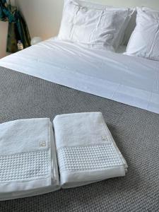 duas toalhas brancas estão sentadas numa cama em T2 Saint-Denis -Jardin de l'Etat em Saint-Denis