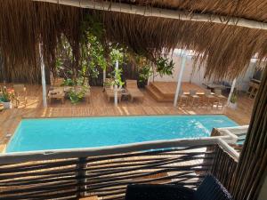 a swimming pool with a straw umbrella and a resort at NENA BEACH CLUB & HOTEL in Barú