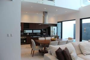 una cucina e una sala da pranzo con un divano bianco e un tavolo di Casa Moderna de 4 Pisos Con Rooftop Vista Al Mar a Isla Mujeres