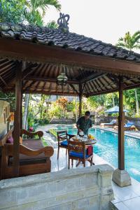 a man sitting at a table under a pavilion next to a pool at Alam Jiwa Ubud in Ubud
